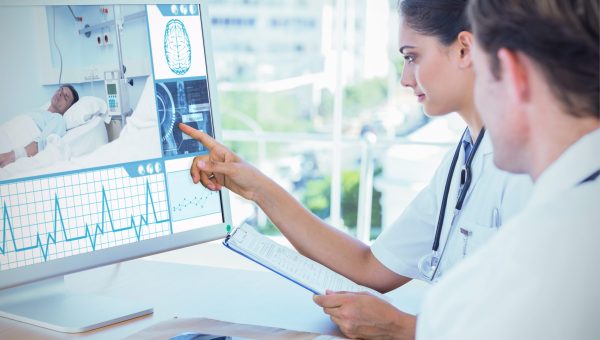 Doctor pointing at the screen of a computer against white background with vignette Doctor pointing at the screen of a computer against white background with vignette